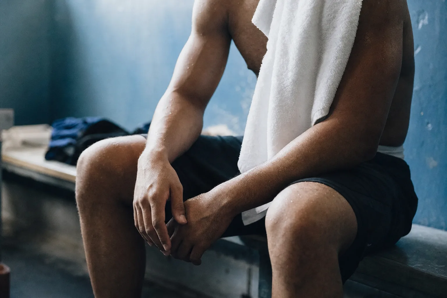 Sportif en récupération après l'effort, serviette sur l'épaule, dans un vestiaire
